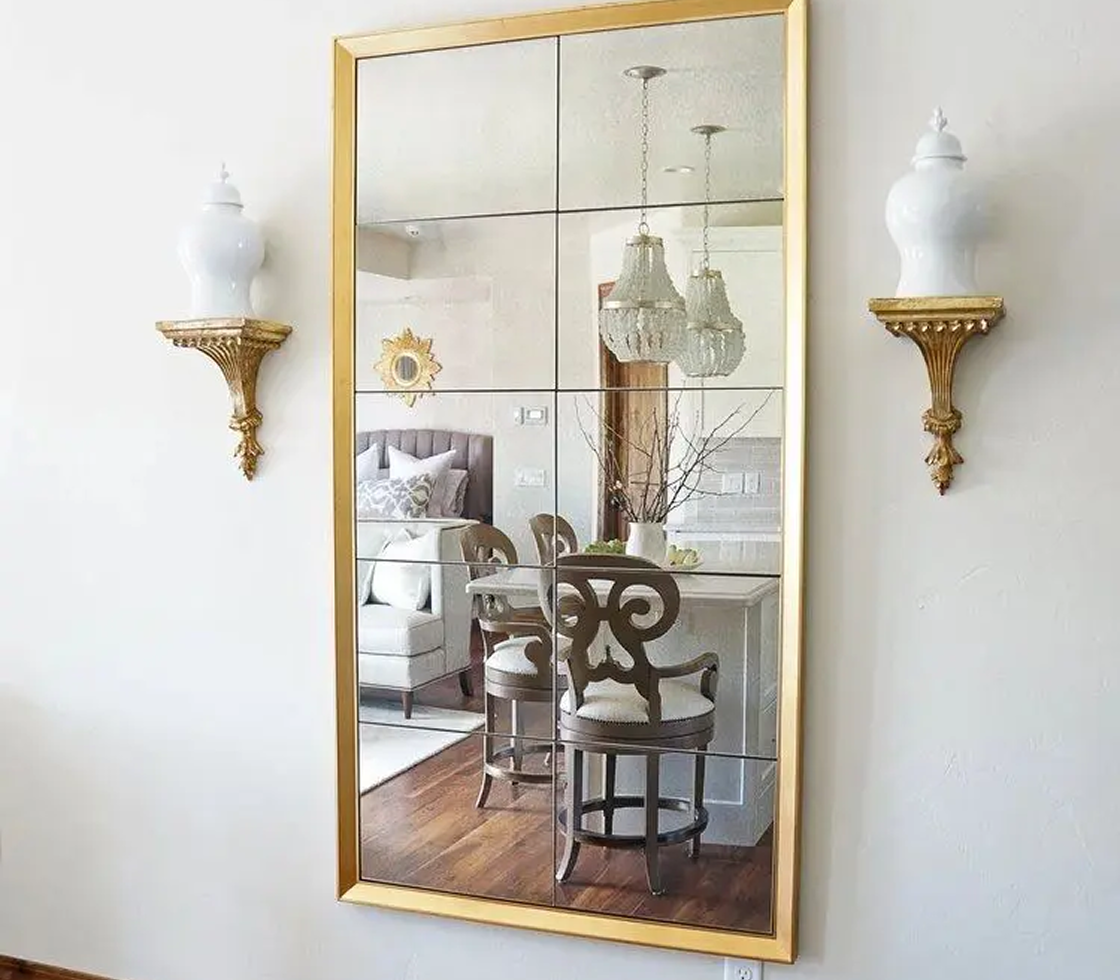 Gold-framed mirror with elegant wall sconces.